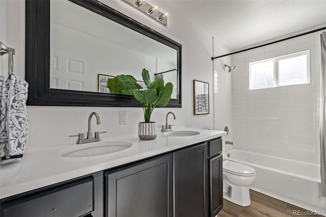 full bath with double vanity, wood finished floors, shower / bath combo, and a sink