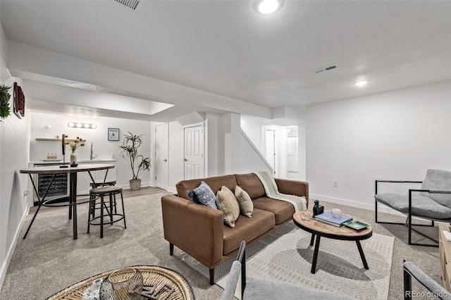 living room featuring recessed lighting, visible vents, light carpet, a textured ceiling, and baseboards