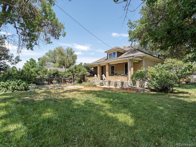 view of front of home featuring fence, a front lawn, and brick siding