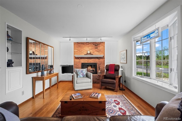 1322 Wicklow St, Boulder, CO 80303 - living room featuring track lighting, light wood finished floors, a brick fireplace, and baseboards