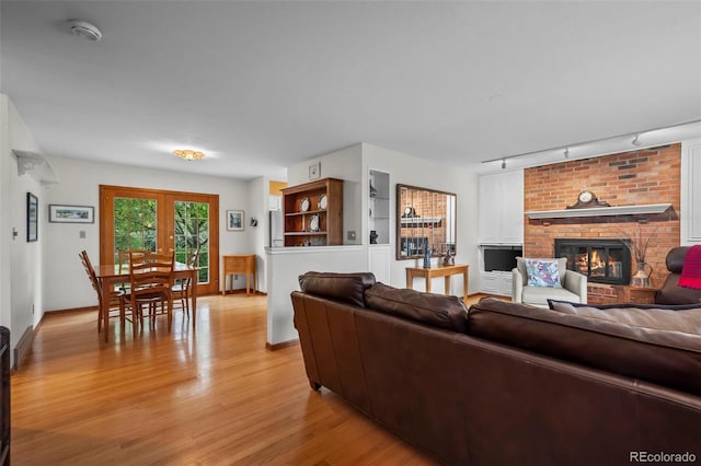 1322 Wicklow St, Boulder, CO 80303 - living room featuring rail lighting, light wood-style flooring, a brick fireplace, and baseboards