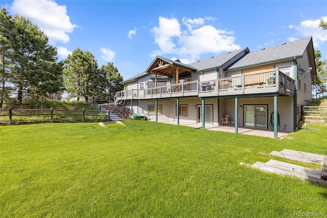 rear view of property featuring a patio area, a wooden deck, and a lawn