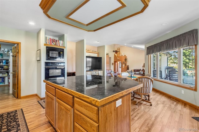 kitchen with a center island, tile counters, brown cabinets, black appliances, and light wood finished floors