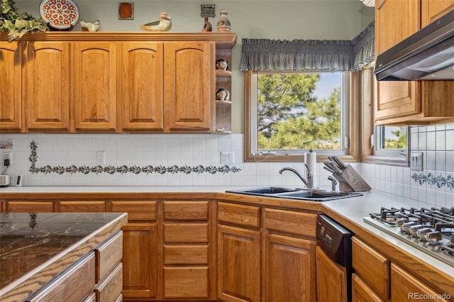 kitchen featuring dishwasher, wall chimney range hood, tasteful backsplash, sink, and stainless steel gas stovetop