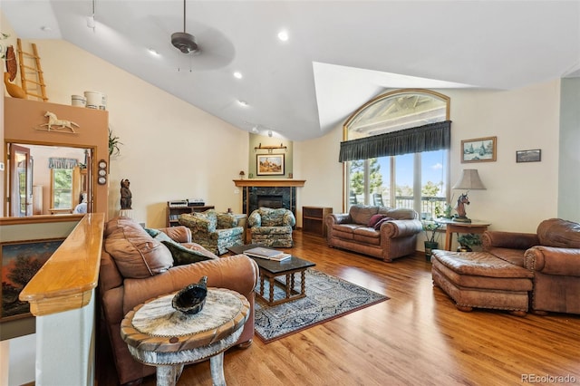 living area featuring ceiling fan, high vaulted ceiling, wood finished floors, and a tile fireplace