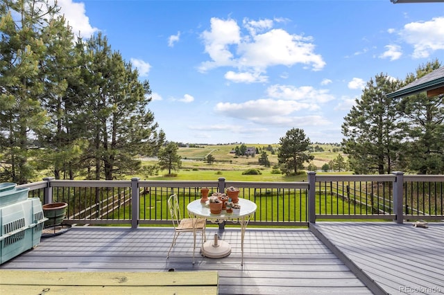 wooden terrace with a rural view and a yard