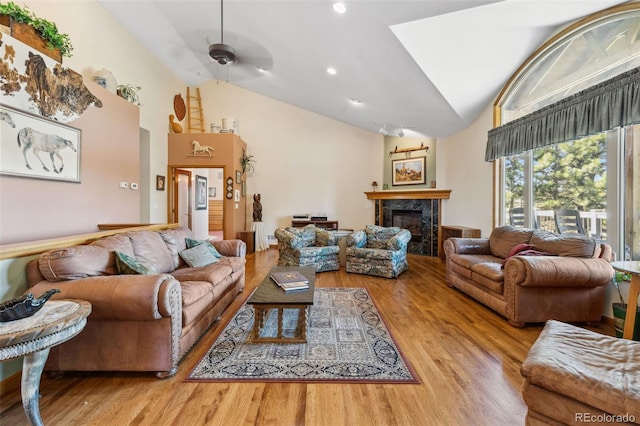 living room with a premium fireplace, lofted ceiling, wood-type flooring, and ceiling fan