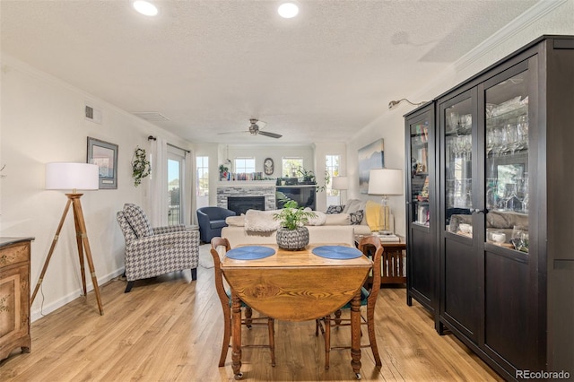 dining room with light hardwood / wood-style floors, crown molding, and a fireplace