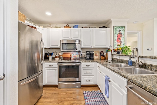 kitchen featuring ornamental molding, appliances with stainless steel finishes, light hardwood / wood-style flooring, and white cabinets