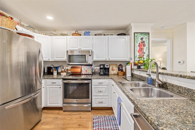 kitchen featuring appliances with stainless steel finishes, sink, light wood-type flooring, white cabinetry, and crown molding