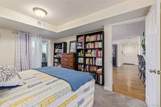 bedroom with a textured ceiling and light hardwood / wood-style flooring