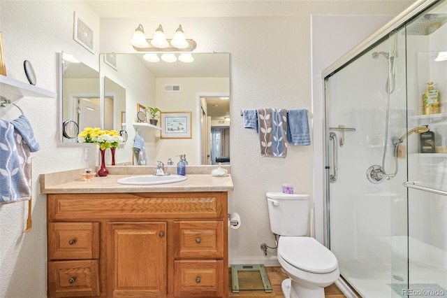 bathroom featuring vanity, a shower with shower door, and toilet