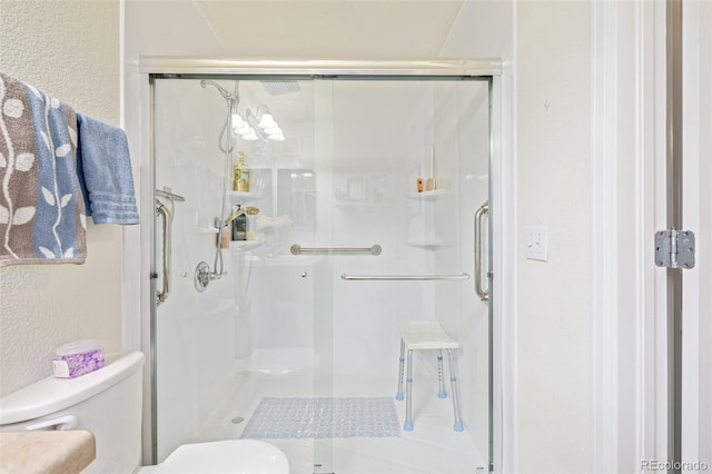 bathroom featuring a shower with door and toilet