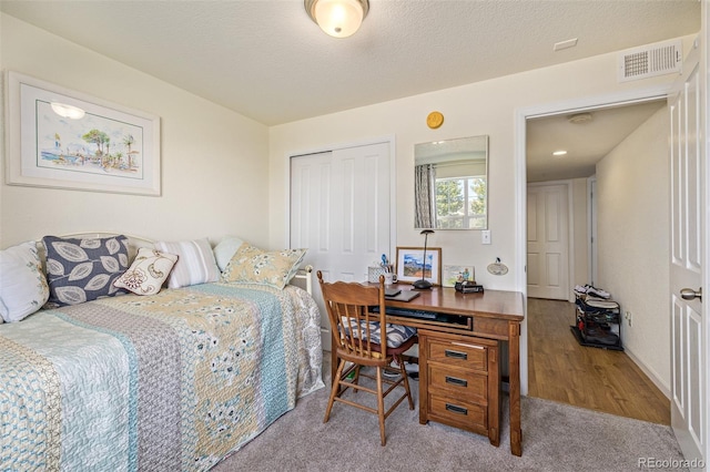 bedroom with a textured ceiling, light wood-type flooring, and a closet