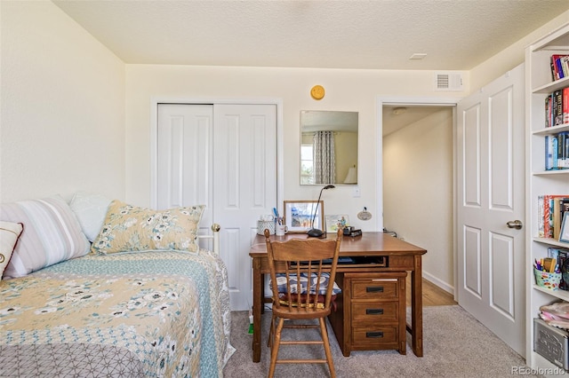 carpeted bedroom with a textured ceiling and a closet