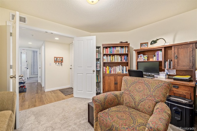 office with light hardwood / wood-style flooring and a textured ceiling