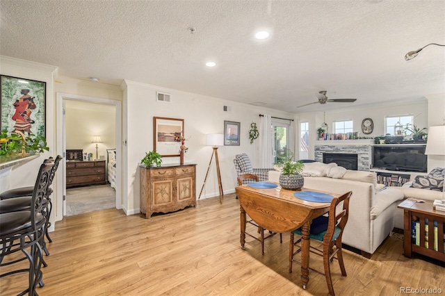 dining area featuring light hardwood / wood-style floors, a textured ceiling, plenty of natural light, and a fireplace