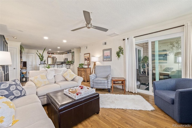 living room with ceiling fan, hardwood / wood-style flooring, and a textured ceiling