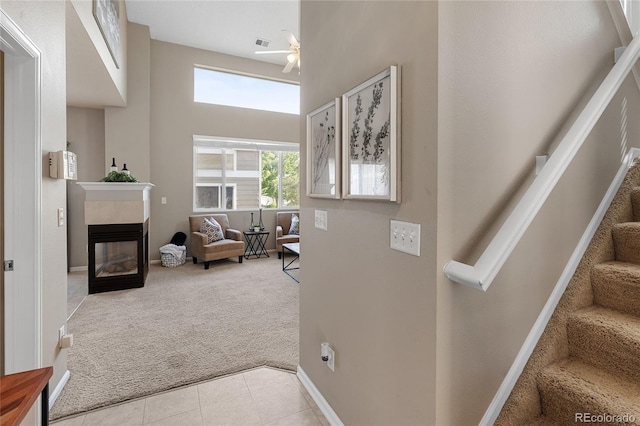 15125 E Bayaud Pl, Aurora, CO 80012 - stairs featuring carpet flooring, a towering ceiling, ceiling fan, a multi sided fireplace, and tile patterned floors