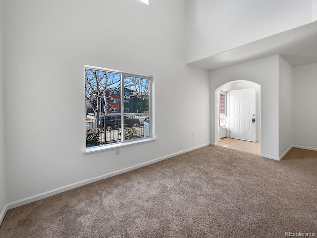 unfurnished room featuring light carpet, a wealth of natural light, and a high ceiling