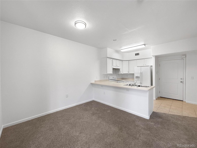 kitchen with light carpet, kitchen peninsula, white appliances, white cabinets, and sink