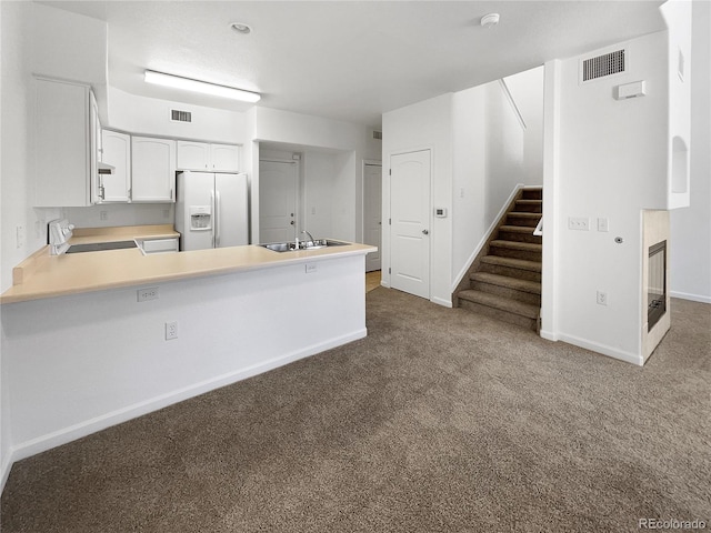 kitchen featuring white cabinetry, kitchen peninsula, carpet floors, stove, and white refrigerator with ice dispenser