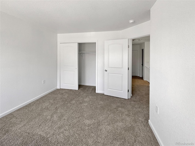 unfurnished bedroom with dark carpet, a closet, and a textured ceiling