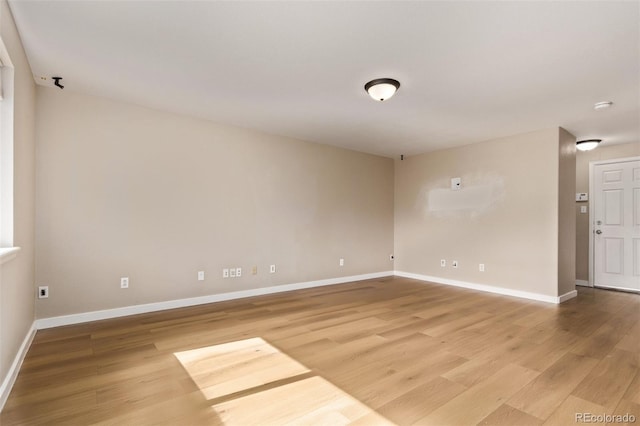 unfurnished room with light wood-style flooring and baseboards