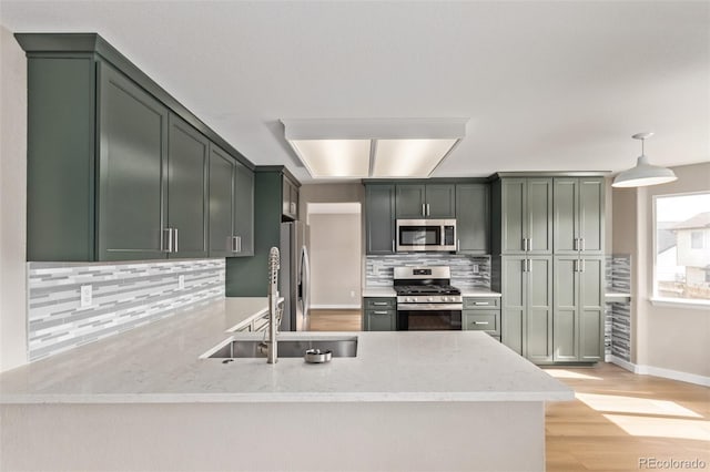 kitchen featuring light stone counters, light wood-style flooring, stainless steel appliances, a peninsula, and decorative backsplash