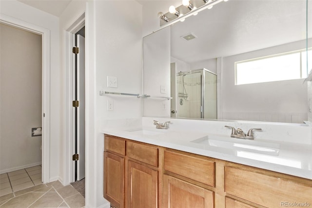 full bath featuring double vanity, tile patterned floors, a sink, and a shower stall