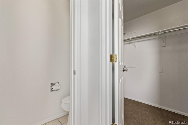 bathroom featuring toilet, tile patterned flooring, and baseboards