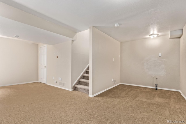 below grade area with carpet, visible vents, stairway, and baseboards