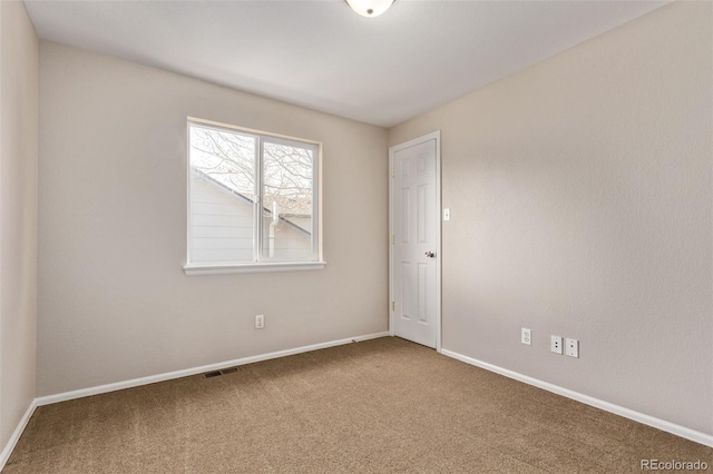 empty room with carpet, visible vents, and baseboards