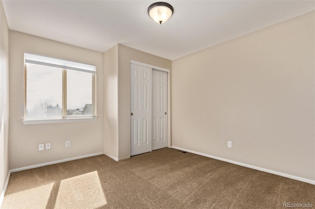 unfurnished bedroom featuring a closet, baseboards, and carpet flooring