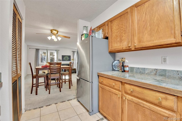 kitchen featuring a textured ceiling, stainless steel fridge, ceiling fan, and light carpet