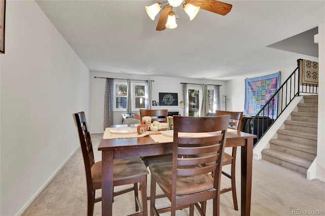 carpeted dining area with a textured ceiling, ceiling fan, and a wealth of natural light