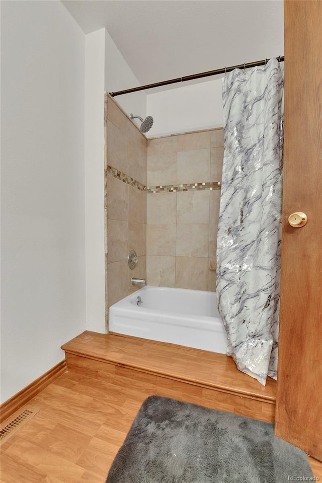 bathroom featuring wood-type flooring and shower / bath combo with shower curtain