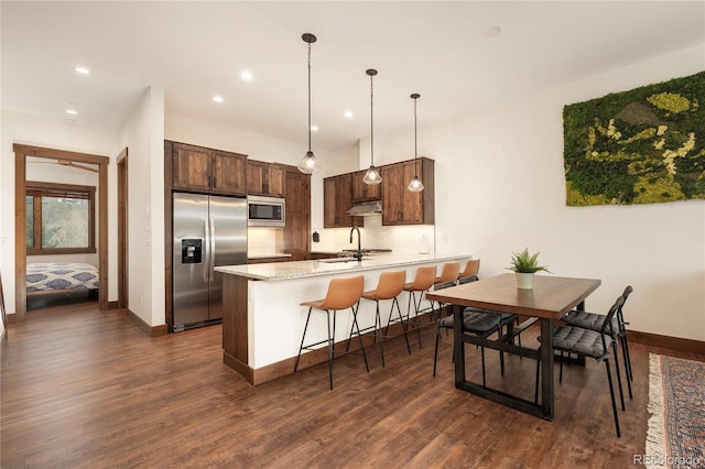 166 Hay Meadow Dr, Fraser, CO 80442 - kitchen with appliances with stainless steel finishes, a peninsula, dark wood-type flooring, under cabinet range hood, and baseboards