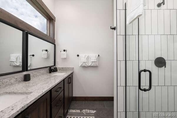 166 Hay Meadow Dr, Fraser, CO 80442 - bathroom with a stall shower, double vanity, tile patterned floors, and baseboards