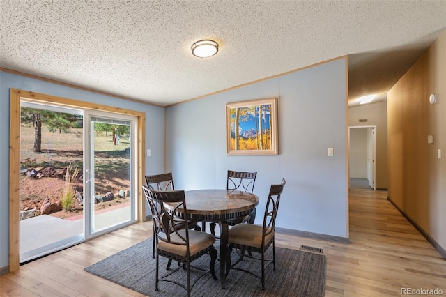 dining space featuring a textured ceiling and light wood-type flooring