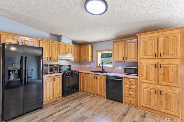 kitchen featuring sink, a textured ceiling, light hardwood / wood-style flooring, black appliances, and vaulted ceiling