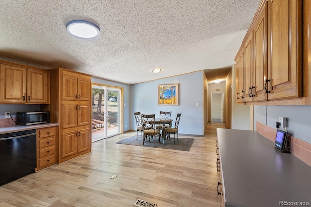 kitchen with black dishwasher, light hardwood / wood-style floors, and a textured ceiling