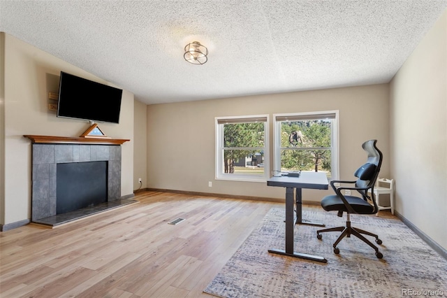 office space featuring a textured ceiling, a fireplace, and light hardwood / wood-style flooring