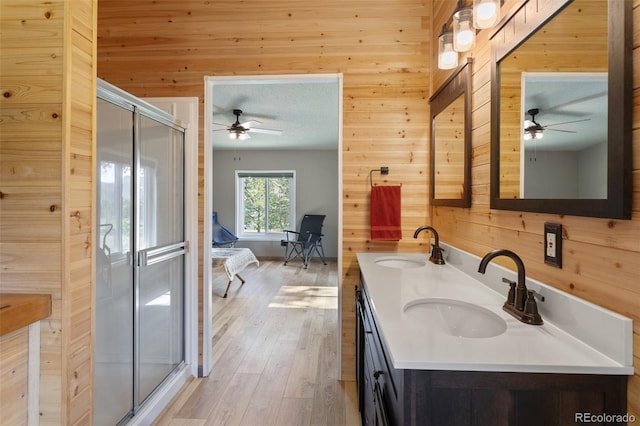 bathroom featuring wood walls, vanity, a textured ceiling, wood-type flooring, and a shower with door