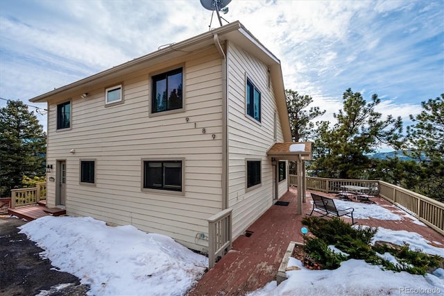 view of snowy exterior with a wooden deck