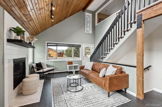 living room featuring dark wood-type flooring, track lighting, a fireplace, and wooden ceiling