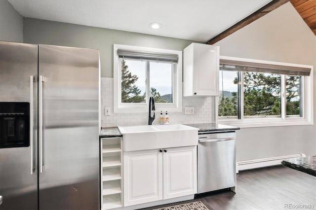 kitchen featuring appliances with stainless steel finishes, tasteful backsplash, white cabinetry, sink, and baseboard heating