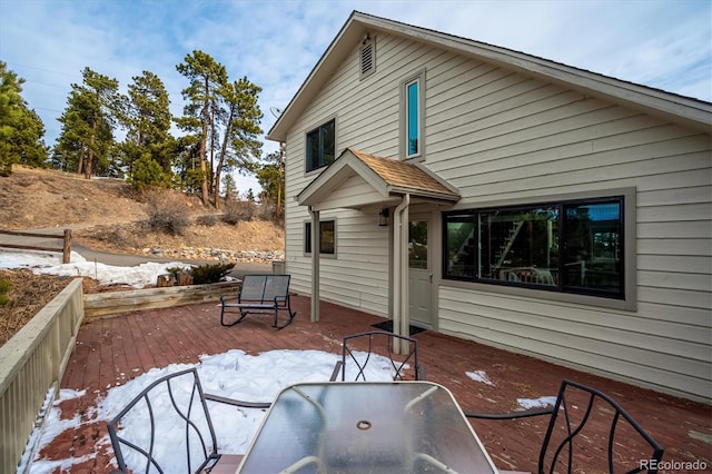 snow covered rear of property with a wooden deck