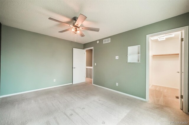 15660 E Purdue Dr, Aurora, CO 80013 - unfurnished bedroom featuring baseboards, visible vents, carpet, ceiling fan, and a walk in closet
