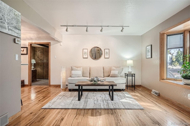 living area with light wood-style flooring, baseboards, and visible vents